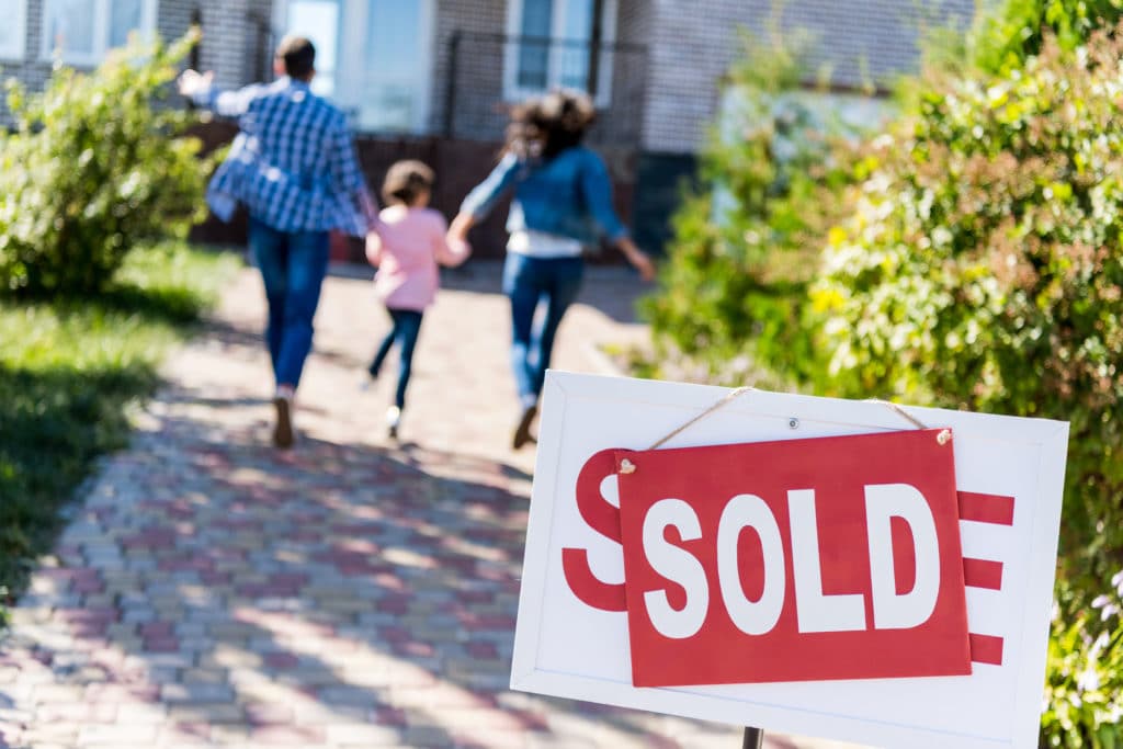 family running to new house with sold signboard on foreground