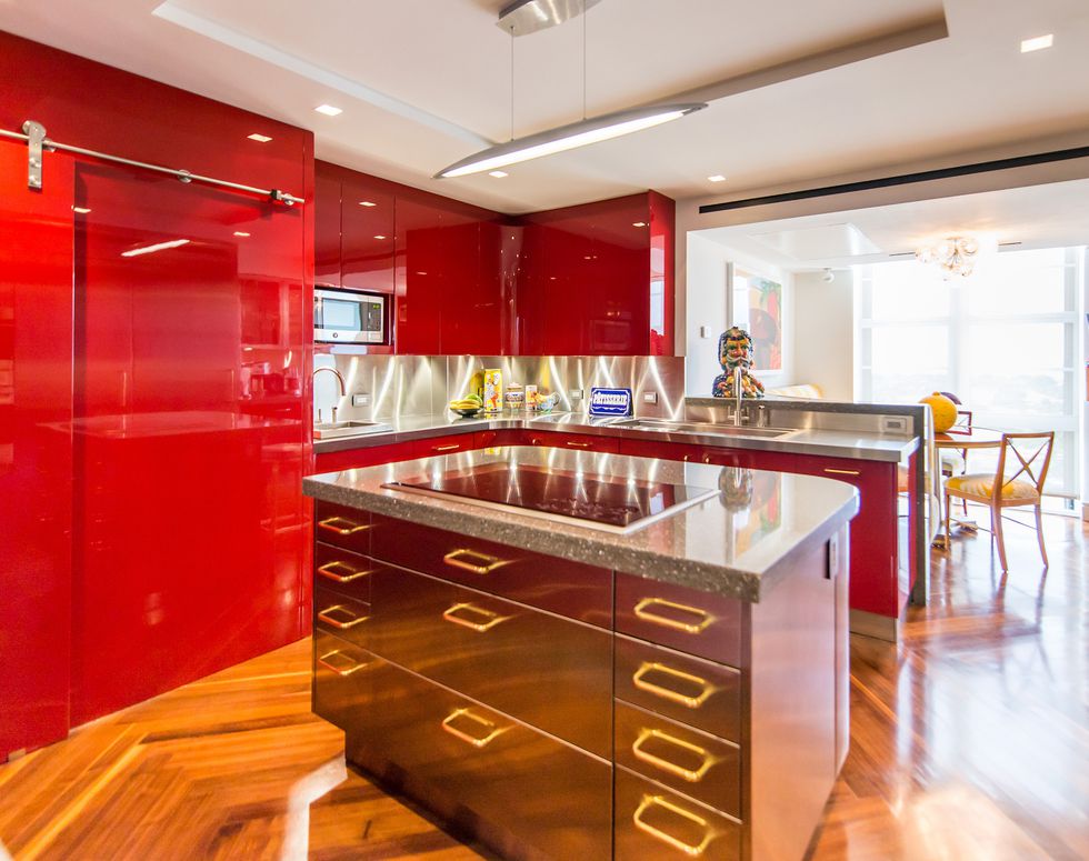 Bright kitchen with shiny red cabinets and coper island.