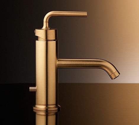 Gold sink spout in a bathroom.