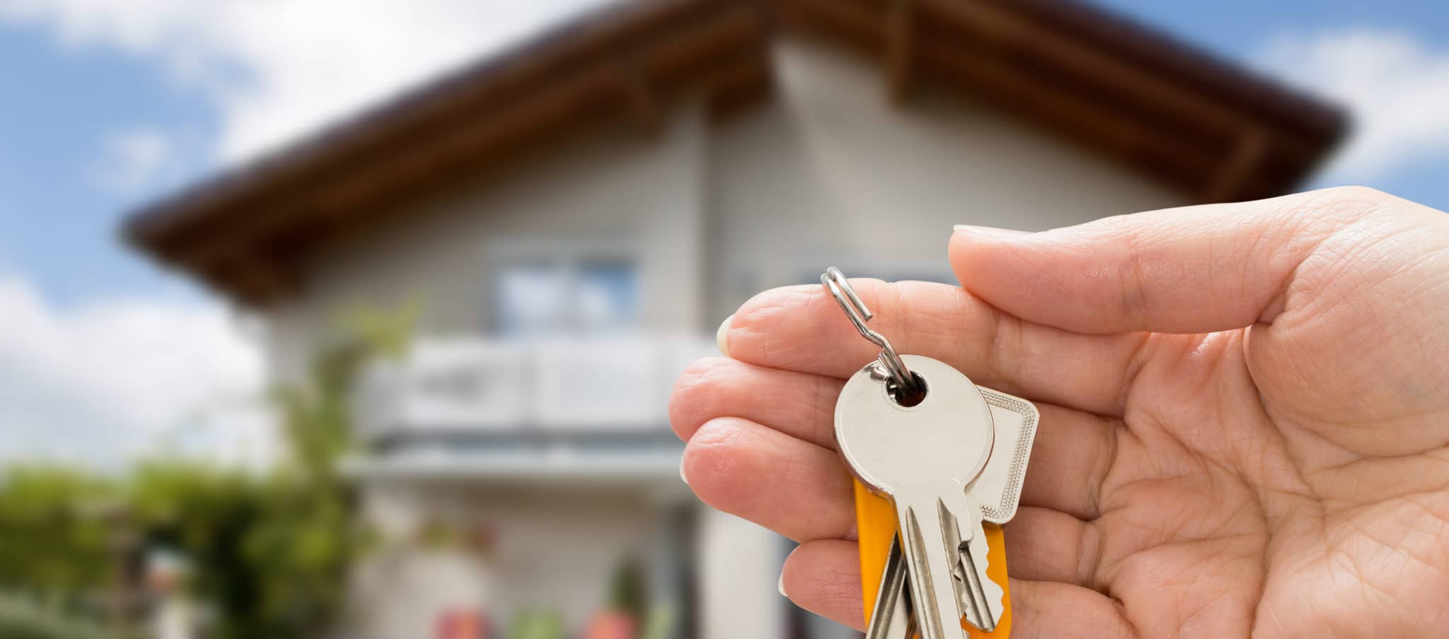 Person holding keys to their new home after purchase on the real estate market.