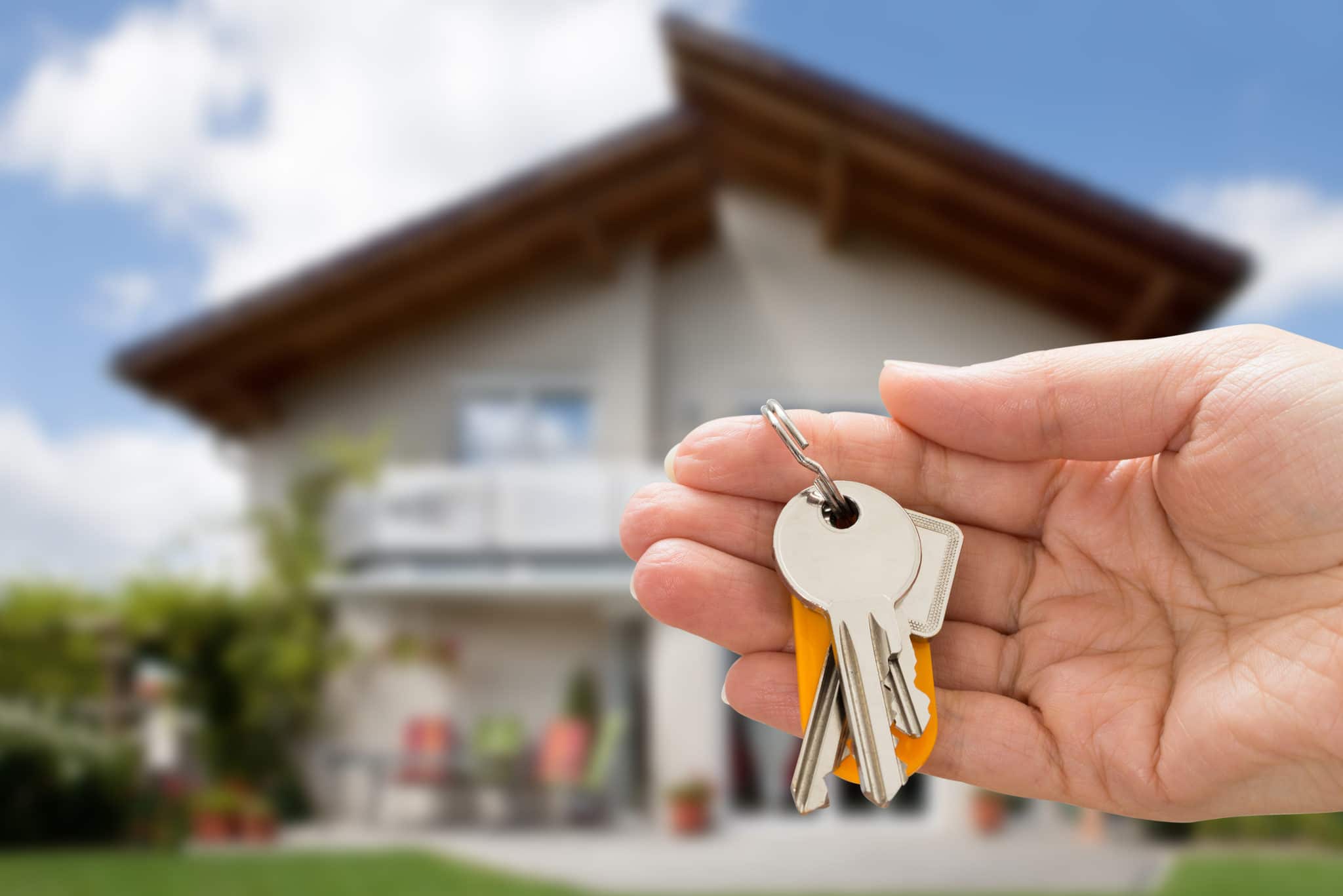 Person holding keys to their new home after purchase on the real estate market.